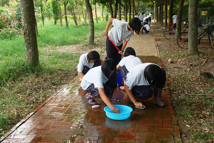 福智教育園區的學生們正認真洗刷紅磚道上的青苔。