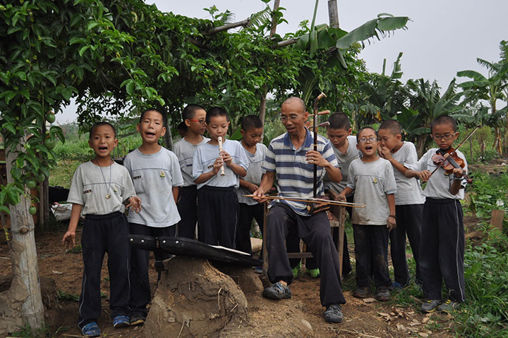 福智國民小學的江國華老師（中）和他的學生們在有機農場中舉辦戶外演唱會。