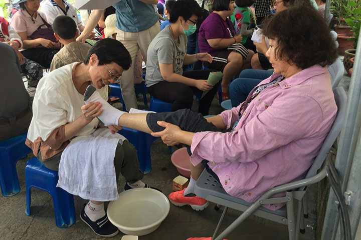 陳淑英（圖左穿白衣者）在感恩禮讚園遊會的「洗腳報親恩」站中，幫媽媽們洗腳。
